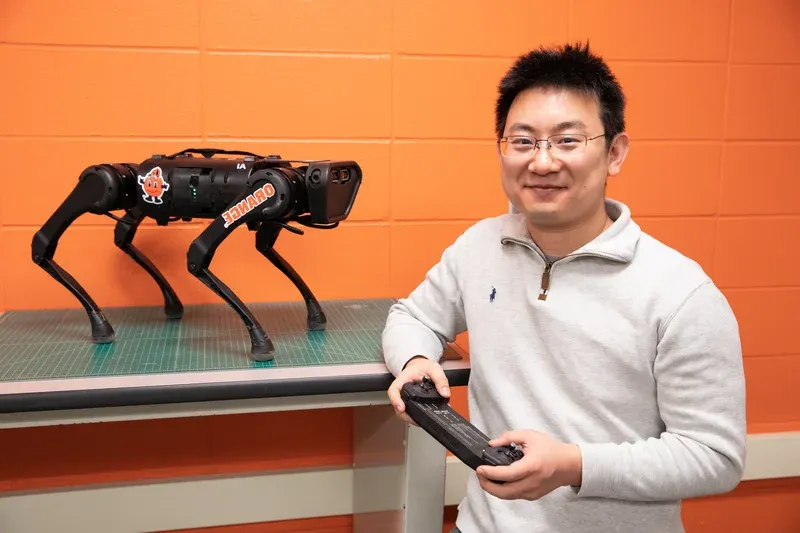 Professor poses with quadruped robotic dog.